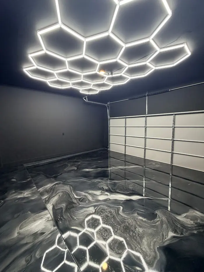 Black and silver metallic epoxy garage floor under hexagon lights by 210 Epoxy Pros
